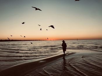 Woman standing at beach during sunset