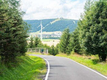 Road amidst trees and landscape against sky