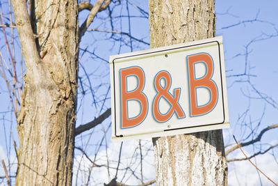 Low angle view of information sign on tree trunk