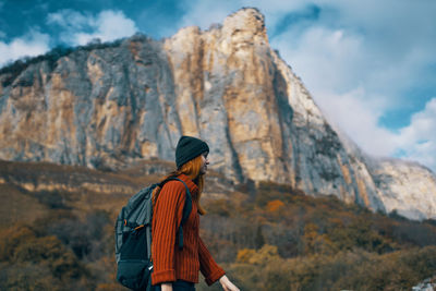 Low angle view of person standing on rock against mountain