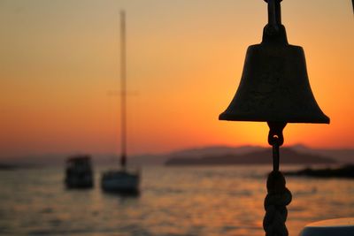 Close-up of silhouette pole against sea during sunset