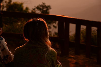 Rear view of woman standing against sky during sunset