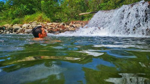 Portrait of woman swimming in waterfall