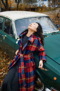 Young asian woman standing near retro car