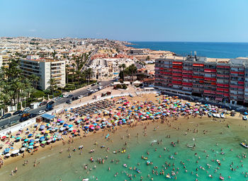 Aerial view of people at beach against clear blue sky in city