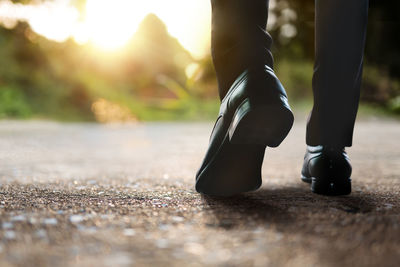 Low section of man walking on road