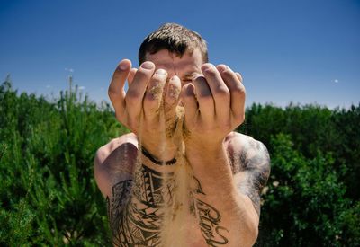 Man with arms raised on field against sky