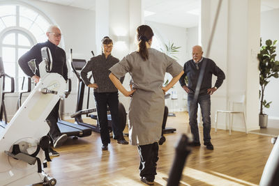 Female nurse assisting elderly men and women to exercise at retirement home