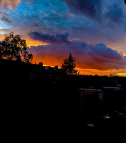 Silhouette trees and buildings against sky during sunset