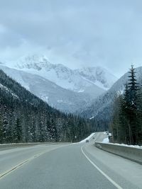 Road amidst snowcapped mountains against sky