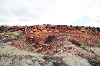 Stack of logs on landscape against sky