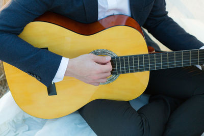 Man's hands playing music at wooden acoustic guitar