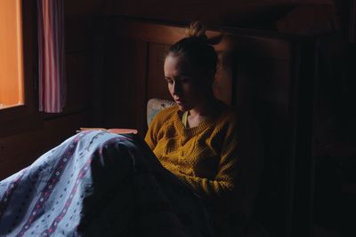 Woman reading book on bed in wooden cottage