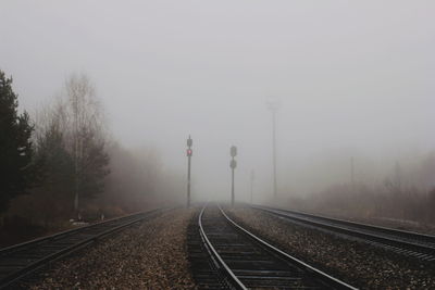 Railway tracks in foggy weather against sky