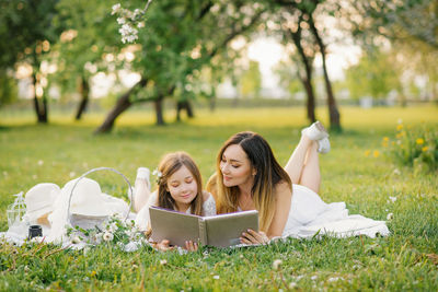 Caucasian family, mother and daughter together watching a family photo album in spring at a picnic