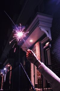 Cropped hand of woman holding sparkler at night