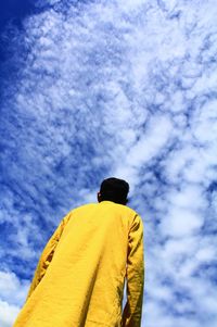 Rear view of man standing against yellow sky