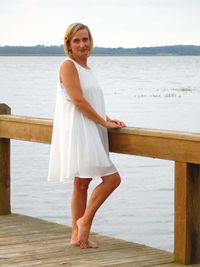 Side view portrait of woman standing on pier over sea