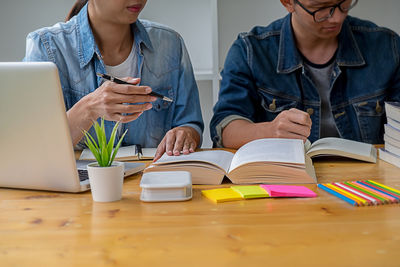 Midsection of man using mobile phone while sitting on table