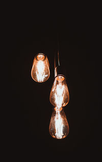 Close-up of illuminated light bulb against black background