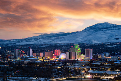 Snowy sunset skyline of reno, nv with snowcapped mountains in the background