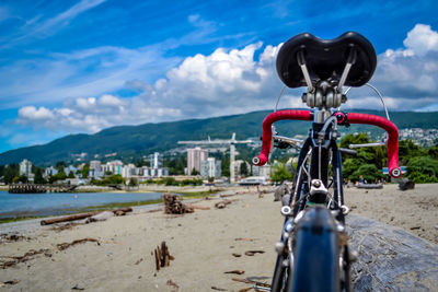 Bicycle parked at beach against cloudy sky