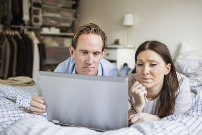 Couple using laptop while lying in bed at home