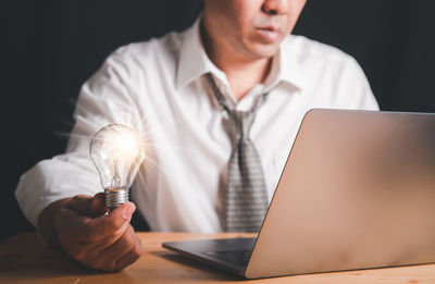 Midsection of man using mobile phone while sitting on table