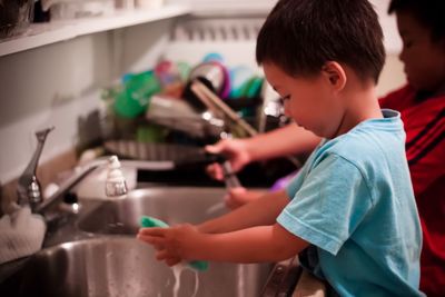 Side view of boy washing dishes at kitchen sink