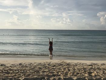 Rear view of man standing at beach against sky