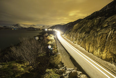 High angle view of light trails on road by rocky mountains at sunset