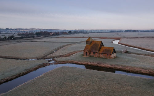 Old abandoned building by lake against sky