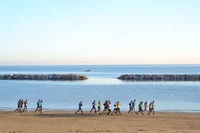 People on beach against clear sky