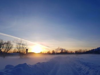 Snow covered landscape against sky during sunset
