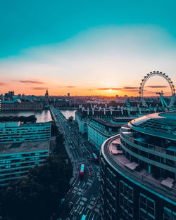 High angle view of ferris wheel in city against sky at sunset