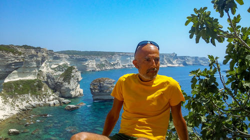 Man standing on rock against blue sky