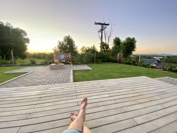 Low section of person relaxing by plants against sky