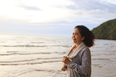 Young woman looking at sea shore against sky