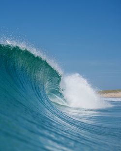 Water splashing in sea against clear blue sky