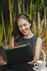 Mid adult woman holding coffee cup on smart phone