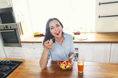 Portrait of woman eating food at home