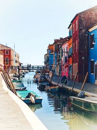 Sailboats moored on canal by buildings against sky