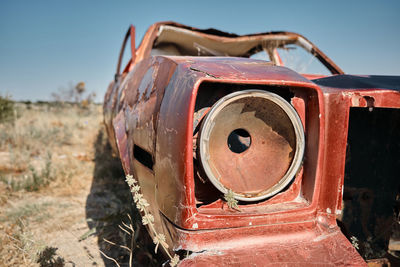 Old rusty car on field against sky