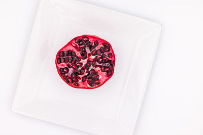 Food shot of a half pomegranate on a white plate cropped in studio in top view