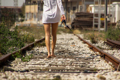 Low section of woman walking on railroad track