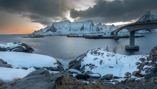 Scenic view of sea and snowcapped mountains against sky during sunset