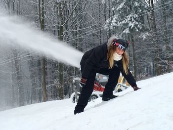 Portrait of woman by snowmobile against trees on snow covered hill