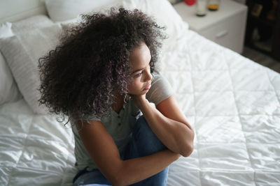 High angle view of girl sitting on bed at home