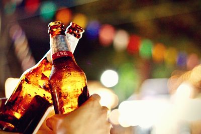 Close-up of hand holding glass bottle against blurred background