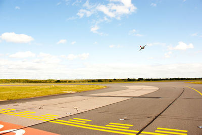 Airplane flying over road against sky